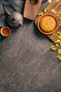 中秋节传统饮食理念——美丽的月饼在黑石板桌上用茶、糕点模具、花、特写、复制空间