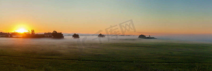 晴朗天空背景摄影照片_黎明在薄雾中的草地上, 对天空晴朗的背景。薄雾中的草原黎明.