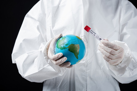 cropped view of scientist in white hazmat suit holding globe and covid-19 omicron variant test isolated on black