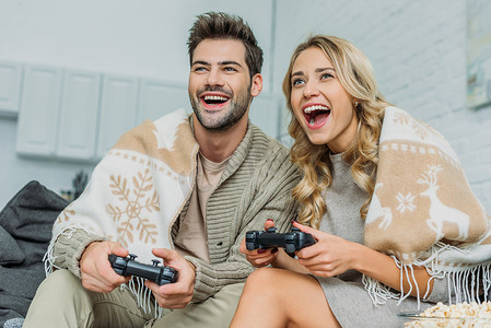 美丽的年轻夫妇玩视频游戏和乐趣一起在沙发上在家里