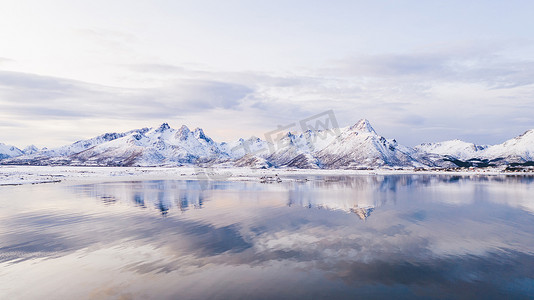 叹为观止摄影照片_挪威海水中覆盖着覆盖着白雪的高山岩石山峰，鸟瞰着令人叹为观止的景象。冬季罗浮敦全景迷人的峡湾，宁静的自然美 