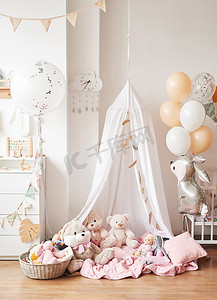 风筝玩具摄影照片_斯堪的纳维亚风格的白色室内儿童房，卧室，托儿所。有天篷的婴儿床。木制货架和玩具天篷帐篷、纺织品风筝和气球.