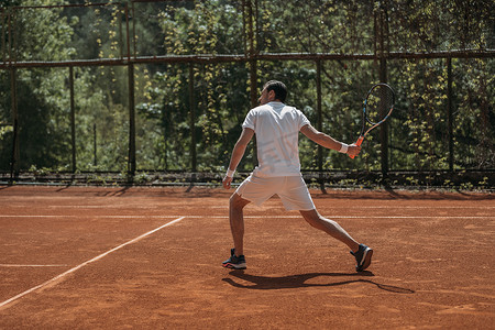 网球少年摄影照片_少年网球运动员准备在户外球场服役