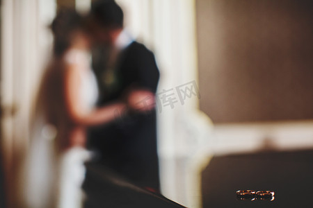 结婚戒指躺在黑色的钢琴，虽然新婚夫妇在亲吻