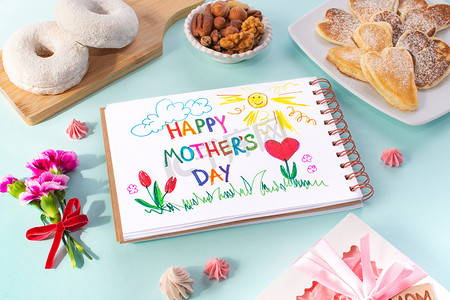 母亲日早餐卡片是由一个孩子做的.祝您母亲节快乐。在一个彩色的背景。煎饼的形式有心脏、甜甜圈、坚果、康乃馨、礼物和一张明信片，由孩子们为妈妈做.