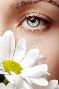 特写宏的美丽女性的眼睛，完美的造型的眉毛。清洁皮肤，时尚自然化妆。良好的视力。春天看起来自然与洋甘菊花