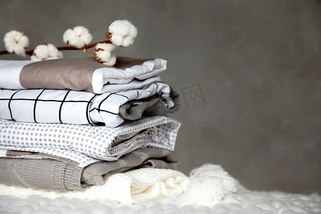 一堆堆叠叠在一起的保暖毛毯,图案各异,棉枝呈灰色背景.织毛毯生产以植物为基础的天然纤维。制造。有机产品