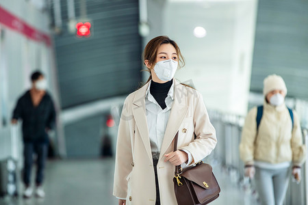 戴口罩的年轻女人走在地铁站里