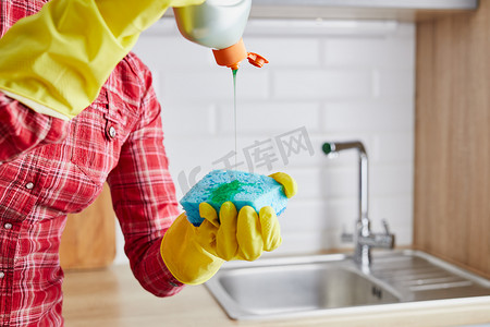 戴手套和海绵的女人。洗碗用的凝胶和泡沫。厨房里的家务活.