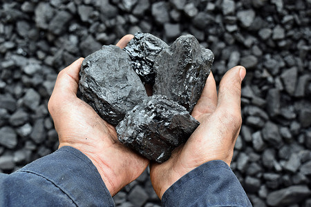 能源开采摄影照片_工人矿工手中的煤。图片可用于煤炭开采、能源或环境保护的理念.