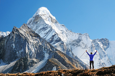 背着背包徒步旅行者到达山峰的峰会。成功的自由和幸福成就在山中。活跃的运动概念.
