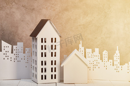 房屋模型在白色木表附近的白纸切割城市在阳光下,房地产概念