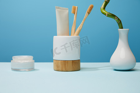 竹杆摄影照片_牙刷、化妆品霜和竹杆支架在桌子和蓝色背景