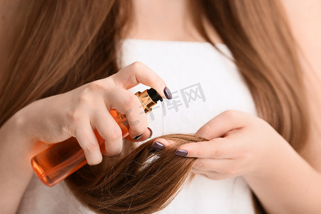 年轻女子应用护发素在她美丽的长发, 特写镜头