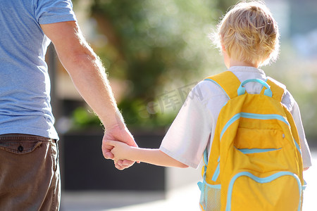 School摄影照片_Little schoolboy with his father goes to school after summer holiday. Parent accompanies or meets the child. Quality education for children. Kids back to school concept.