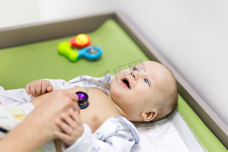 可爱的婴儿在医生的内阁。儿科医生用听诊器检查儿童。微笑健康的孩子。儿童保健与疾病预防概念