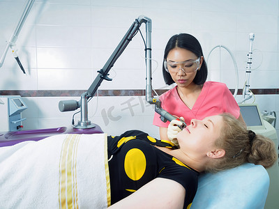 医学美容摄影照片_年轻的亚洲医生女人向病人激光皮肤磨削术在医学美容