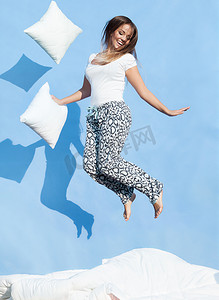 pillow摄影照片_女人抱着枕头在床上跳了起来