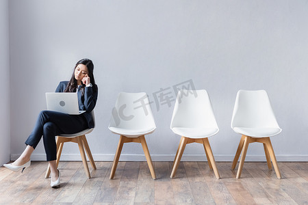 亚洲女商人在等待求职面试时在大厅里使用笔记本电脑 