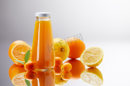 在反光表面上加橙、柠檬和金橘的鲜汁瓶