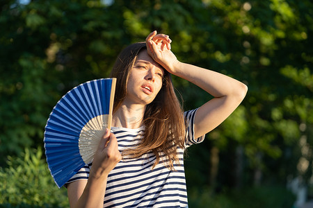 年轻女子在室外中暑.闷热的女孩摸额头很不开心