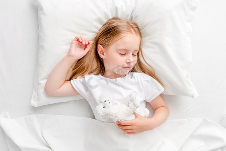 白色床摄影照片_在白色的床上睡觉的小女孩