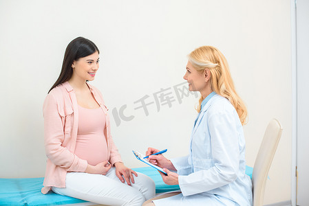 妇产科医生咨询孕妇在诊所和书面在剪贴板