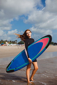 girl in wetsuit with surfboard