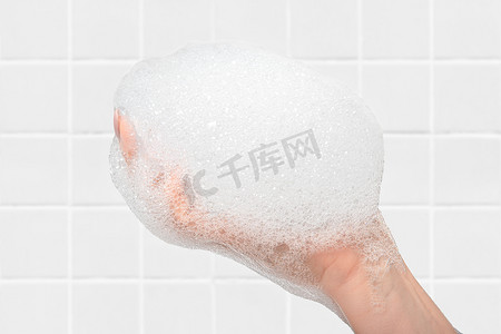 浴室背景上的女性手上的肥皂和泡沫。洗手和洗手