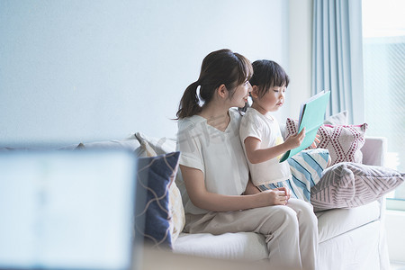 电厂画册摄影照片_母亲和女儿坐在沙发上看画册