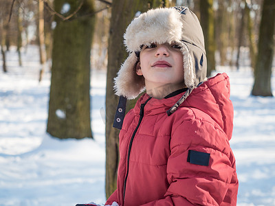 可爱的小男孩在红色夹克在冬天公园背景
