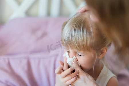 流鼻涕的孩子。妈妈用纸巾把孩子的鼻子吹出来。季节性疾病
