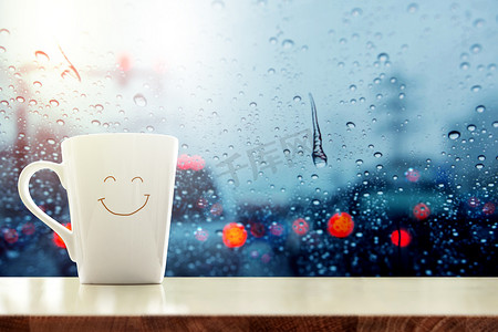 快乐咖啡杯含笑面对玻璃窗口内的桌子上, 
