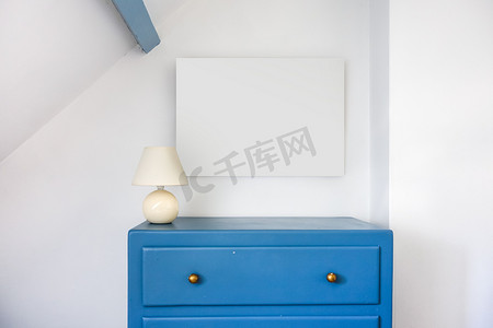 木柜动图摄影照片_空白的画框和蓝色的乡村木柜.白墙背景