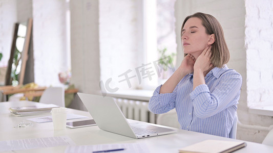 现代办公室中有颈部疼痛的疲倦的年轻女性