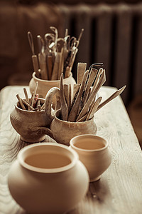 木工陶艺摄影照片_油漆刷与陶艺工具在桌上的碗的特写