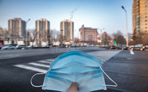 卫生城市标志摄影照片_城市背景下的口罩