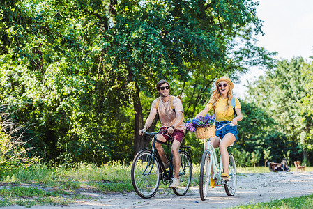 骑情侣摄影照片_年轻快乐的情侣骑复古自行车在公园夏天的一天
