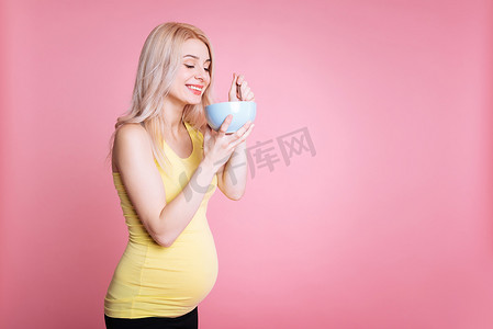粉红色孕妇摄影照片_微笑孕妇吃沙拉