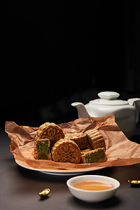 金木水火土字体摄影照片_在黑色的木桌上选择中国月饼、茶壶和金锭的重点