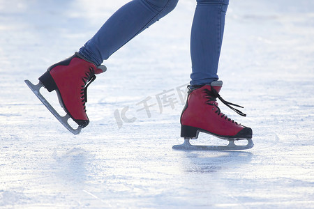 脚踏在溜冰场上的红色冰鞋。业余爱好和休闲。冬季运动