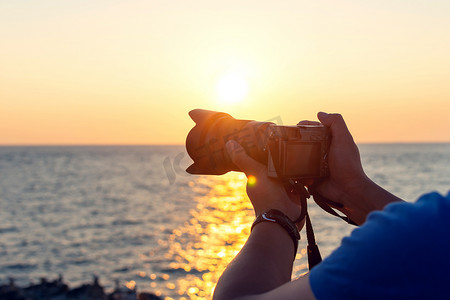 关闭游客在日落背景下用相机拍照. 