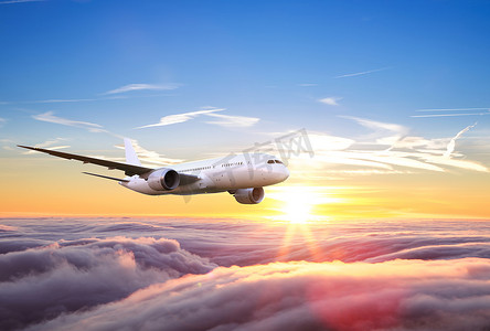 巨大的两层乘客商用飞机在日落时飞越云层上空。快速旅行、节假日和商务的概念.
