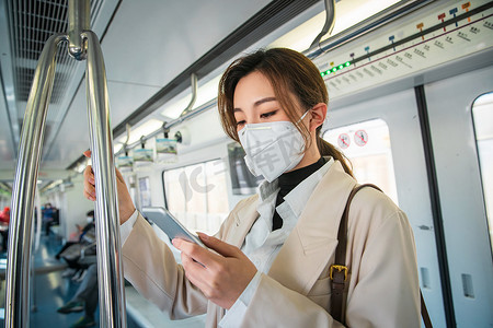 健康绿色城市摄影照片_青年女人在地铁上看手机