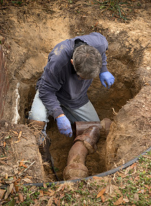 中老年声乐摄影照片_检查老粘土陶瓷下水道管道在洞里的地上的人