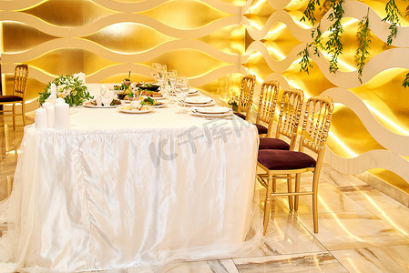 婚礼为新婚夫妇在餐厅与金色的内饰, 自由空间的婚礼主席团。在婚宴上布置优雅的餐桌。新郎新娘和椅子的婚宴桌。豪华装饰