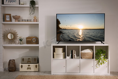 Modern TV set on wooden stand in room. Scene of nature themed movie on screen