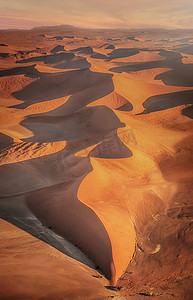 臀部曲线图摄影照片_在纳米比亚的纳米布沙漠，空中俯瞰美丽的沙丘，金光闪闪，形状、线条、曲线和阴影引人注目。垂直图像.