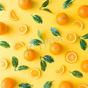 在柔和的黄色背景下, 用橘子和绿叶制作的创意夏日图案。水果最小的概念。平躺.