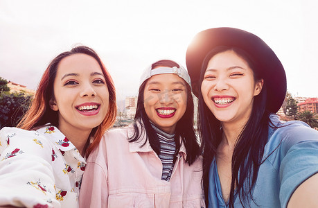 快乐的亚洲女孩自拍与手机手机户外-年轻的社交朋友有乐趣在户外拍摄自己的照片-人, 千年一代和青年生活方式的概念